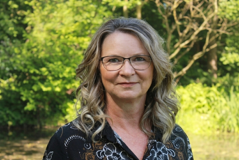 Frau mit Brille lächelt in die Kamera.